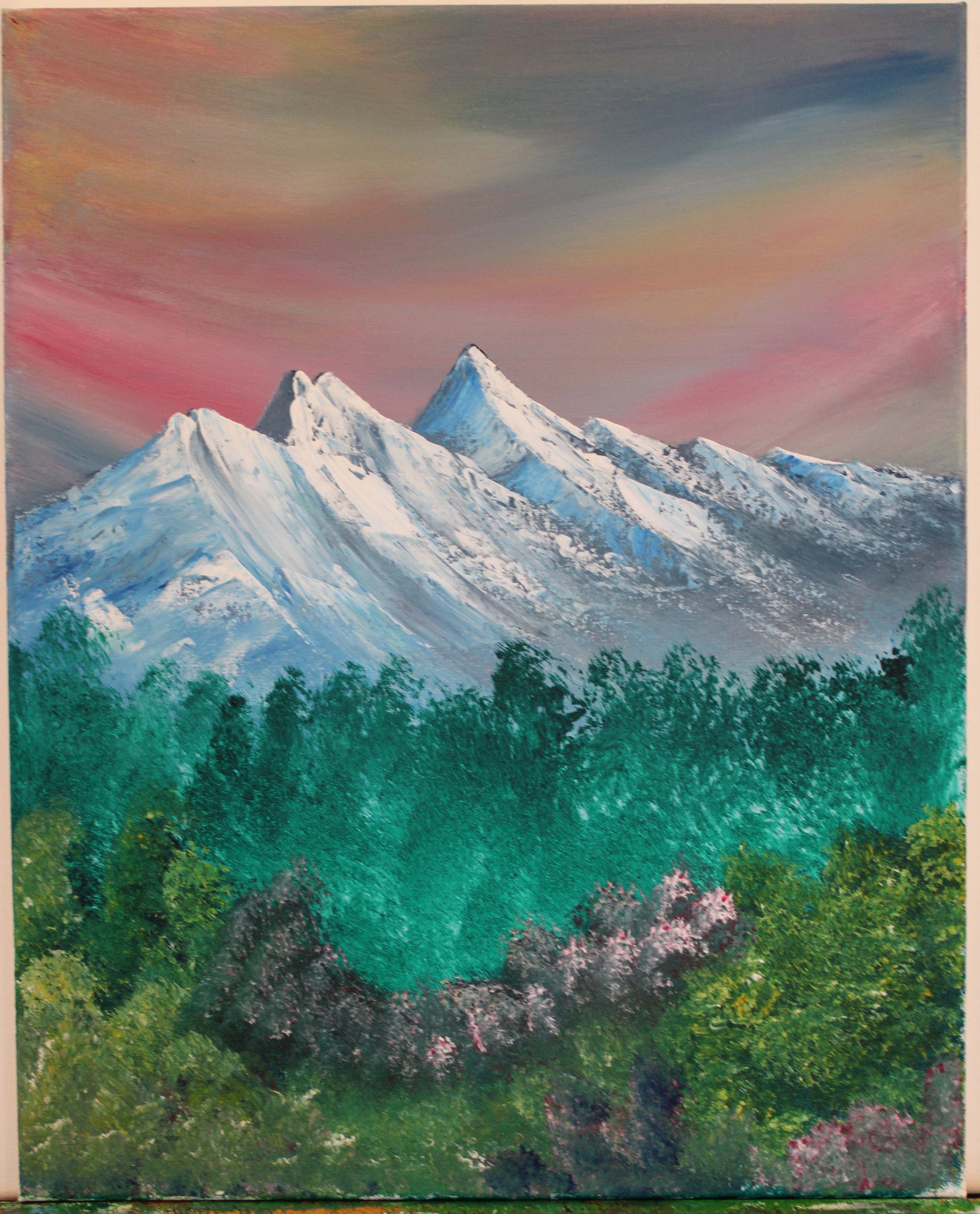 A streaming sky of colors, floating together in one polychromatic mess. A mountain standing still in the center, with a foreground garnished by bushes.