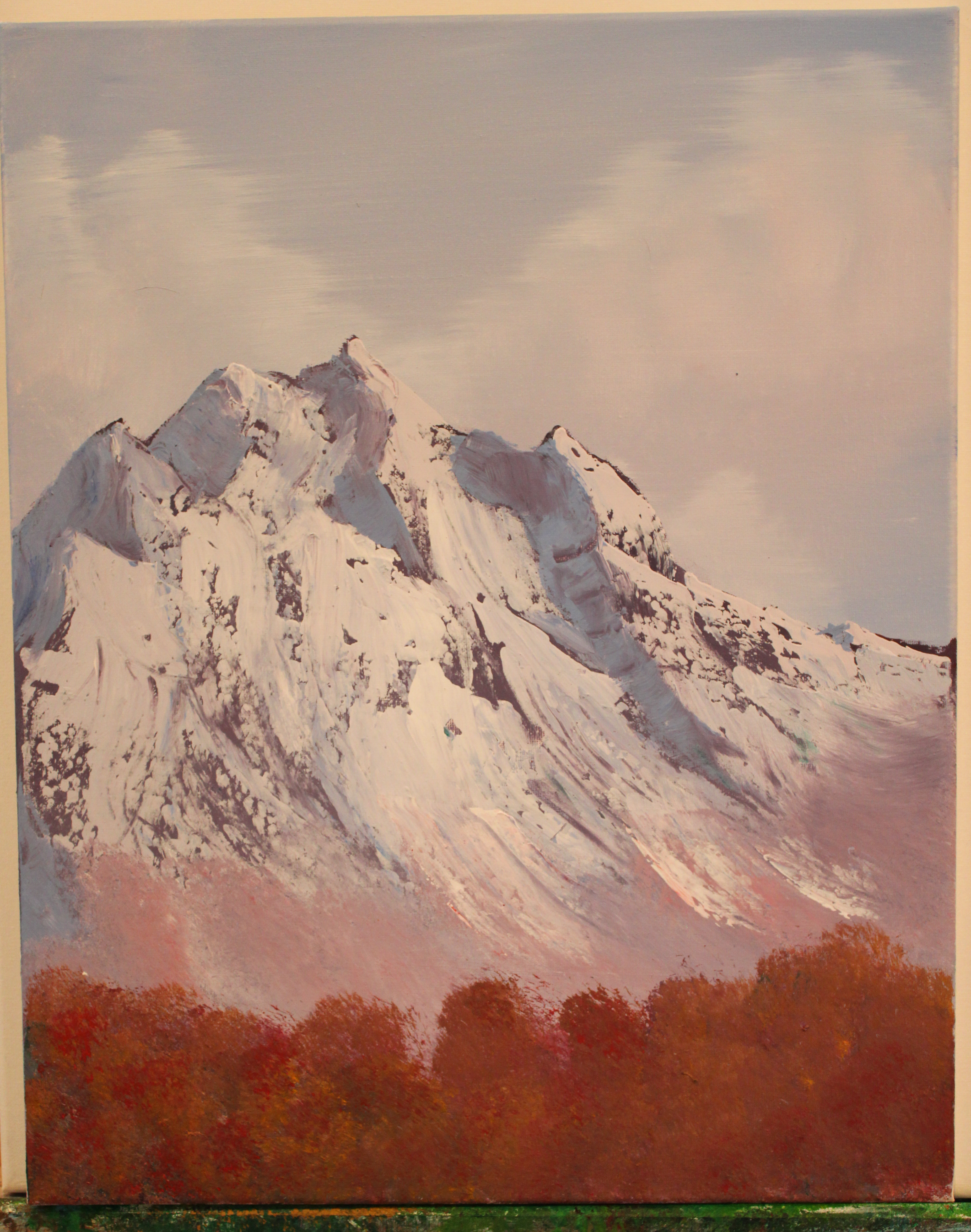 A curvy mountain with a white face facing west, with pink lush at its feet. Foregrounded by warm autumn coloured bushes.