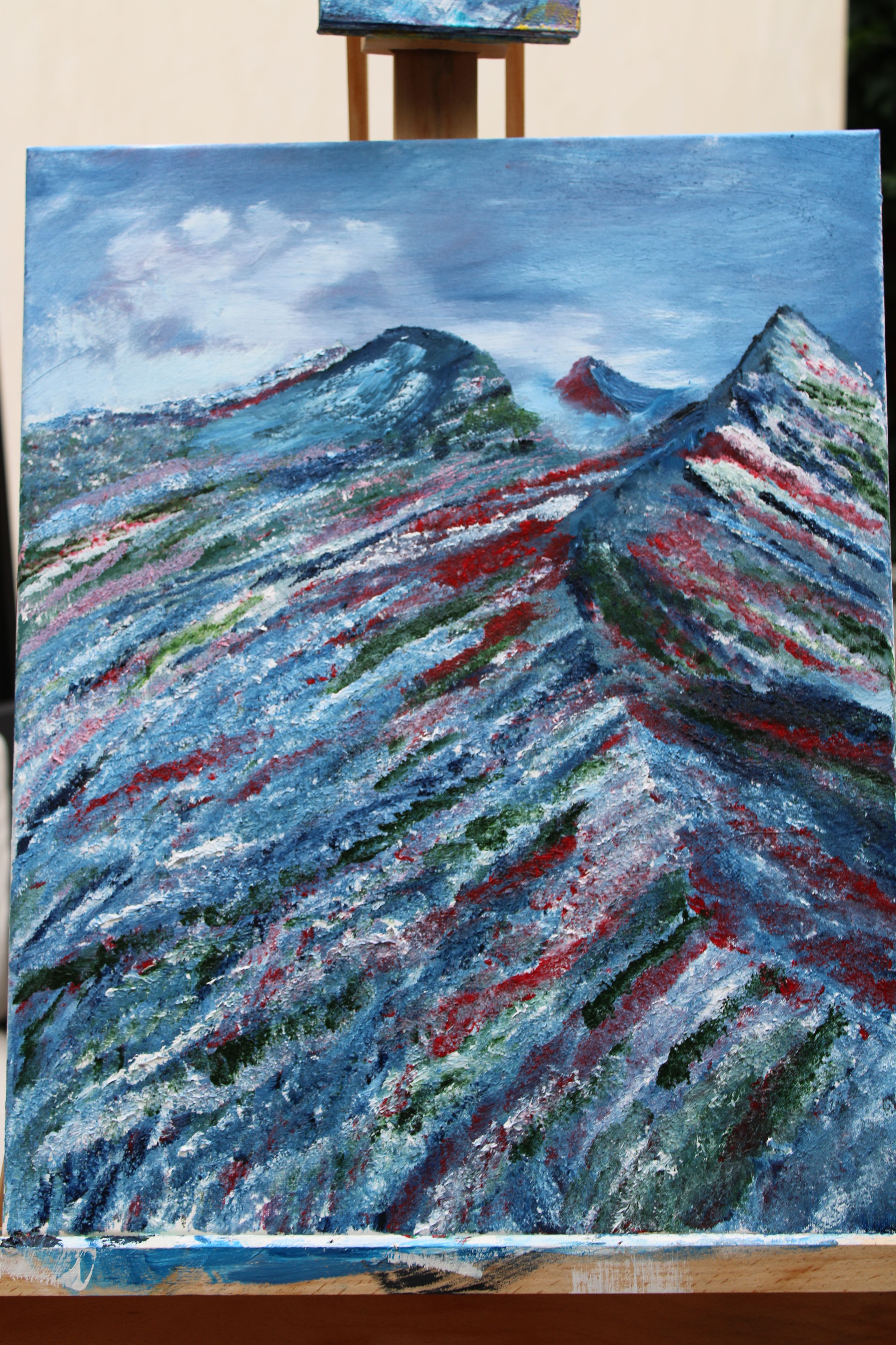 A valley of flowers. Mist rising behind the mountains, with another mountain peak visibkle in the distance. Morning dew, and passing clouds in the sky.